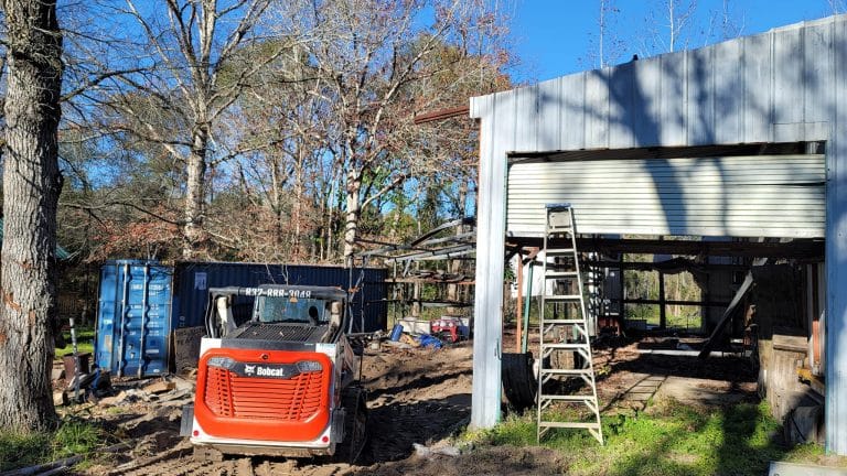 VM Demolition crew with skid steer and roll-off container clearing an old garage structure on a South Belt Houston residential lot