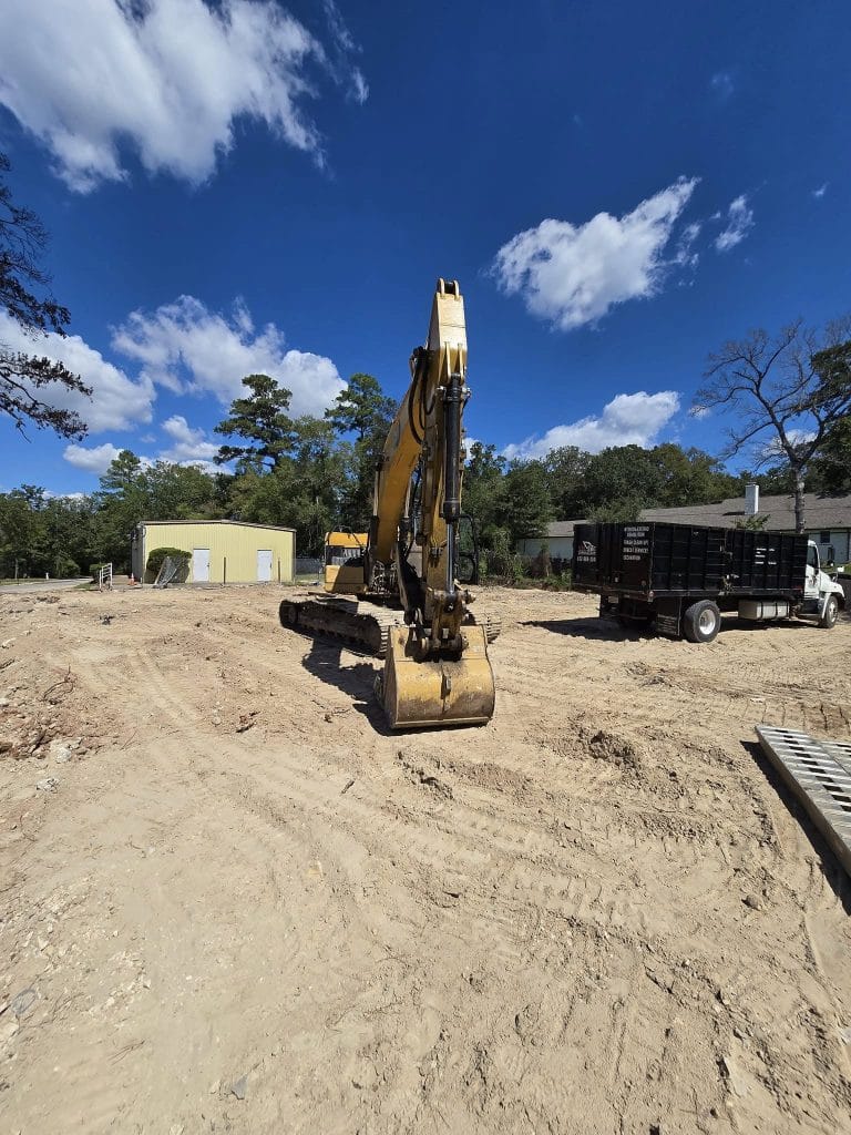 Excavator on a construction site in Houston, TX, surrounded by cleared land and blue skies, illustrating VM Demolition's excavation services for residential and commercial projects.