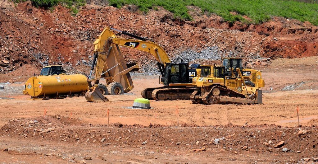 Construction site with heavy machinery, including a CAT excavator and bulldozer, preparing land for demolition and site clearing in Houston, TX.