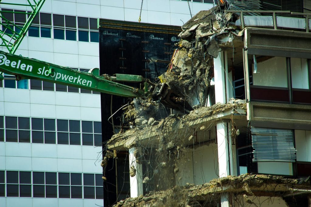 Demolition machinery removing sections of a building, showcasing the process of residential demolition in Houston, TX, with a focus on structural dismantling and debris management.