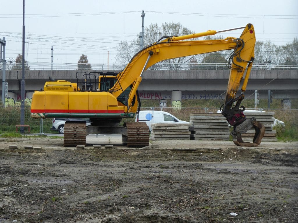 Excavator on a construction site with concrete slabs, representing demolition services offered by VM Demolition in Houston, TX.